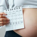 Kobieta w ciąży zaznaczająca datę w kalendarzu, obliczająca miesiące ciąży